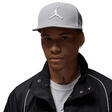 Person wearing a gray cap with a logo on a gray background