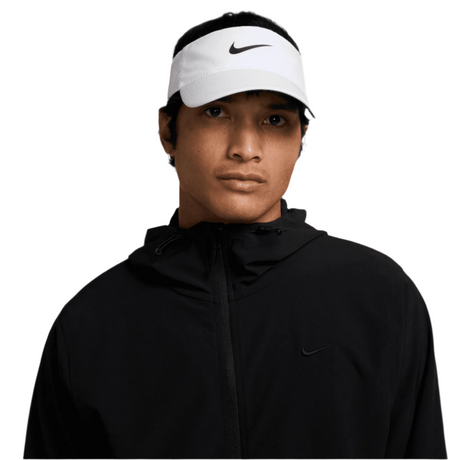 Person wearing a black jacket and white Nike visor on a white background