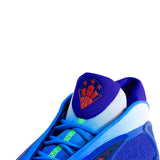 Close-up of a basketball sneaker showing the heel, tongue, and laces. The shoe features a vibrant blue and purple colorway with a white mesh collar, a purple tongue patch with an orange basketball and star logo, and neon green laces.
